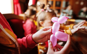 balloon artist sculpting a pink dog